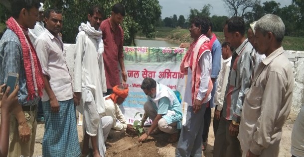 Projekt in Indien zu Laudato Si: Father Anand pflanzt einen Baum, umringt von zahlreichen Helfern