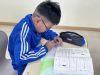 Ein mongolischer Junge macht Hausaufgaben. Bildunterschrift bei Aktivierung: Ein Junge sitzt konzentriert über einem Arbeitsheft.